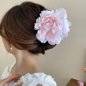 Detailed close-up view of a large pink fabric flower hair clip on an elegant updo hairstyle.