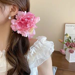 Detailed close-up of a large pink 3D fabric flower hair clip with pearl accent