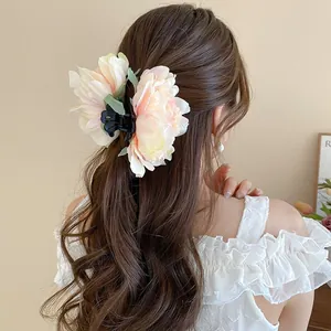 Detailed back view of a romantic 3D peony floral hair claw clip on long wavy brown hair.