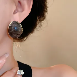 Elegantes pendientes geométricos vintage de resina jaspeada con borde dorado en oreja