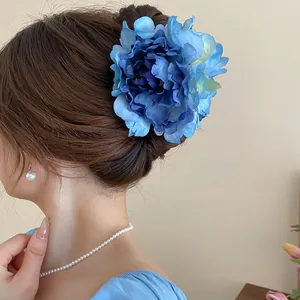 Large blue peony flower hair claw clip styled on a bun for a refined summer hairstyle