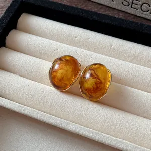 Primer plano de pendientes vintage de resina ámbar jaspeada dentro de un joyero elegante