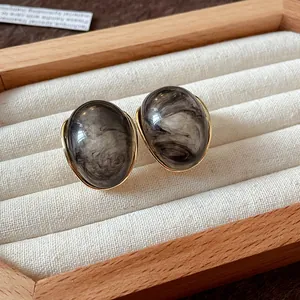 Primer plano exquisito de pendientes retro de resina ahumada con bordes dorados