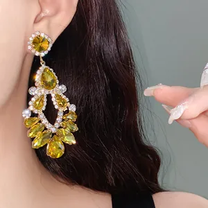 Close-up of ornate geometric earrings with yellow teardrop stones and rhinestones