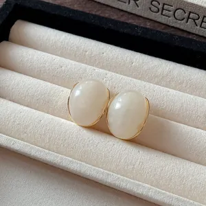 Detalle de pendientes de resina crema vintage en una bandeja de joyería