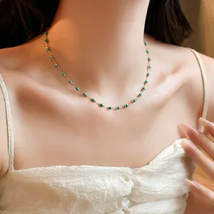 Detail view of a gold-plated beaded necklace with turquoise-colored stones on neck.