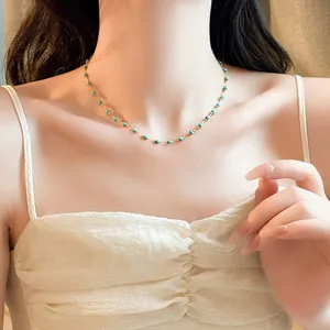 Close-up of minimalist gold plated beaded necklace with turquoise beads on model