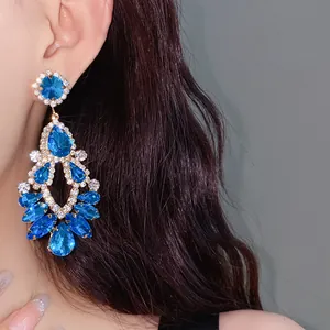 Detailed view of luxury palace style water drop earrings with blue crystals on model