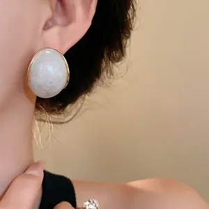 Primer plano de pendientes vintage de resina geométrica con acabado marmoleado blanco