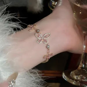 Detailed view of an elegant gold butterfly bracelet with pink and white zircons
