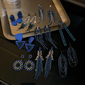 Detailed view of various blue rhinestone tassel and geometric earrings on a silver tray