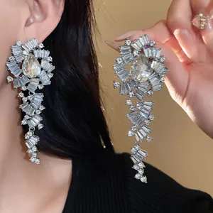 Detail van grote zilverkleurige druppeloorbellen met sprankelende kristallen strass