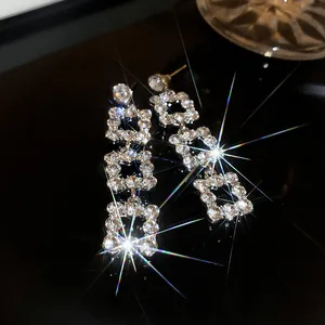 Close-up detail of elegant silver needle dangle earrings with shimmering square rhinestone links
