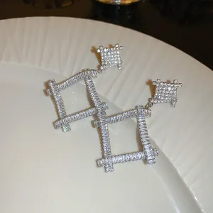 Detail view of silver geometric square earrings encrusted with sparkling clear crystals