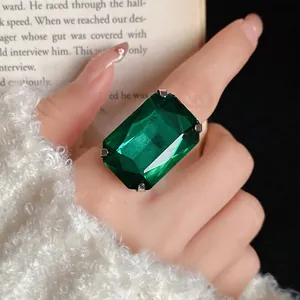 Primo piano di un grande anello con pietra verde taglio smeraldo al dito
