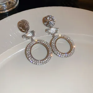 Close-up view of sparkling silver dangle earrings with pave crystals on a white plate