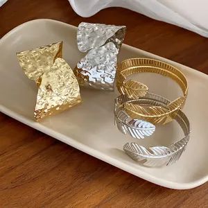 Primer plano de brazaletes minimalistas dorados y plateados con diseño de hojas