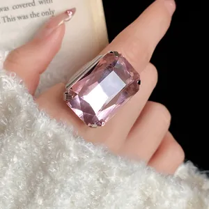 Macro di un anello con gemma rosa quadrata in stile vintage indossato al dito con un maglione.