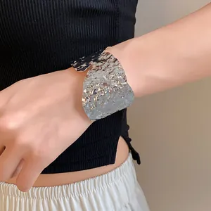 Primer plano de un brazalete geométrico irregular plateado arrugado en la muñeca