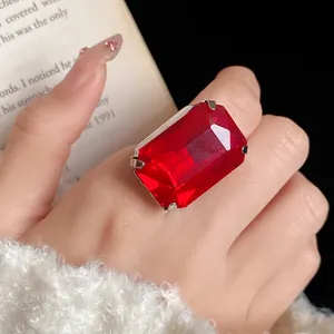 Primo piano di un anello vintage con gemma rossa sfaccettata indossato sul dito.