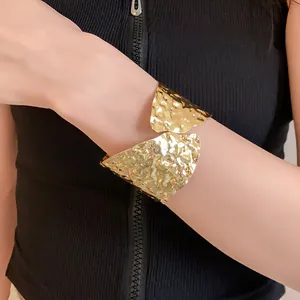 Primer plano detallado que muestra la textura martillada de un brazalete geométrico de oro abierto