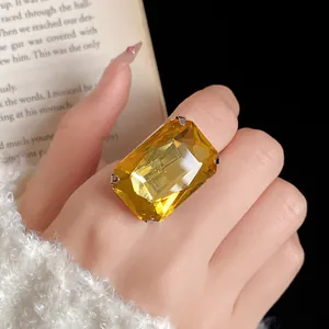 Primo piano di un anello aperto vintage con gemma gialla rettangolare su un dito