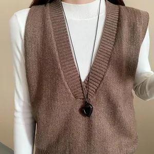Detailansicht der schwarzen Herz-Halskette über einer braunen Strickweste für Damen.