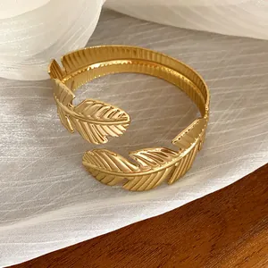 Vista detallada de un brazalete abierto dorado minimalista con elegante diseño de hoja.