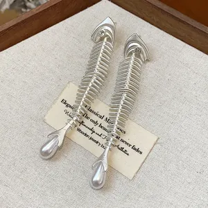 Macro detail of elegant silver-tone fishbone earrings featuring zirconia and pearl drops