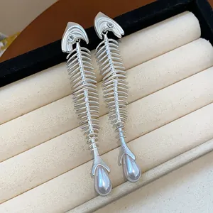Close-up detail showing silver fishbone earrings with zircon and pearl accents