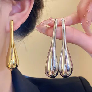 Close-up detail of high-shine polished gold and silver metallic teardrop drop earrings