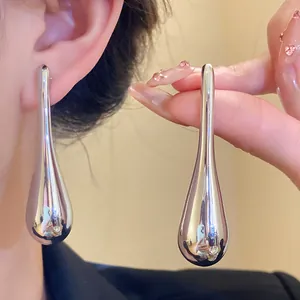 Close-up of large polished silver-tone water drop pendant earrings with mirror finish.