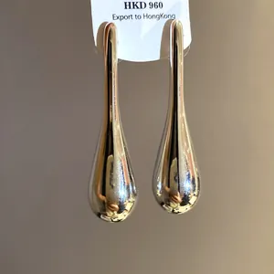 Macro view of polished silver teardrop earrings featuring a sleek minimalist luxury design