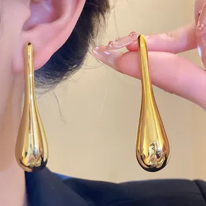 Detail showing the smooth metallic surface and elegant teardrop shape of the gold earrings