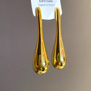Detail view of minimalist gold teardrop earrings with a high-shine polished finish