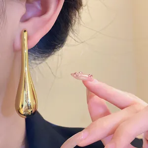 Close-up of elegant gold water drop earrings shown on model for a minimalist fashion look