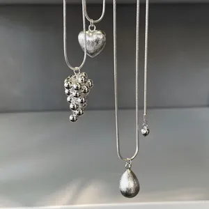 Detailed macro view of elegant silver necklaces featuring brushed heart and teardrop pendants.
