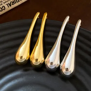 Close-up detail of minimalist gold and silver water-drop earrings with polished finish