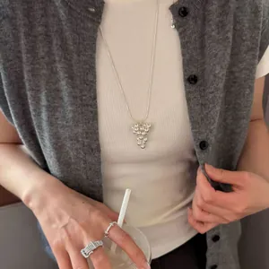 Lifestyle detail of elegant silver grape cluster pendant necklace worn by a model