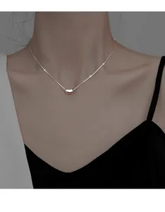 Elegant close-up of a minimalist silver bean pendant necklace on a female model