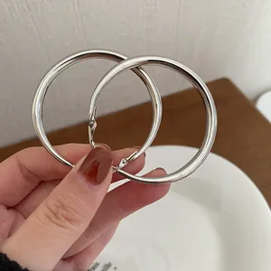 Eleganti orecchini a cerchio in argento minimalisti su un piatto bianco e legno