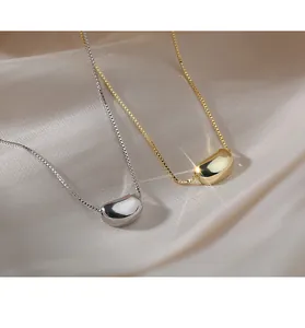 Detailed view of gold and silver bean-shaped pendants on elegant box chains