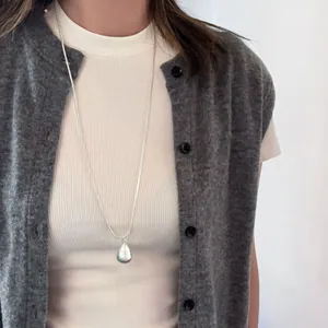 Elegant brushed silver water drop pendant necklace worn on a long chain for daily wear