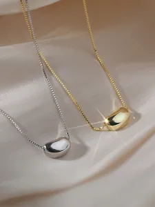 Detail of gold and silver bean pendant necklaces on box chains over silk