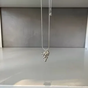 Macro detail of a silver necklace featuring a bunch of spheres on a sleek snake chain.