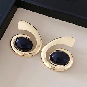 Elegante geometrische spiraal oorbellen met donkere ovale steen in goudkleur
