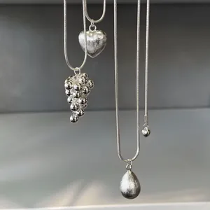 Detail of brushed heart and teardrop silver pendants on adjustable snake chains