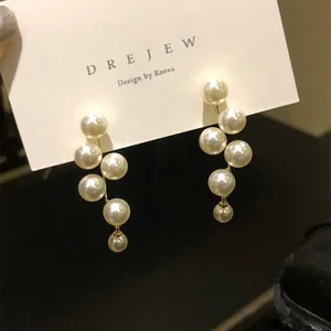 Eleganti orecchini pendenti con perle geometriche su cartellino bianco DREJEW in primo piano