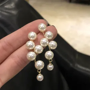Dettaglio dei boucles d'oreilles geometrici a nappa di perle con finitura dorata