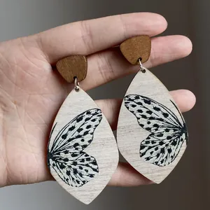 Close-up detail of handmade wood teardrop earrings featuring butterfly wing prints.